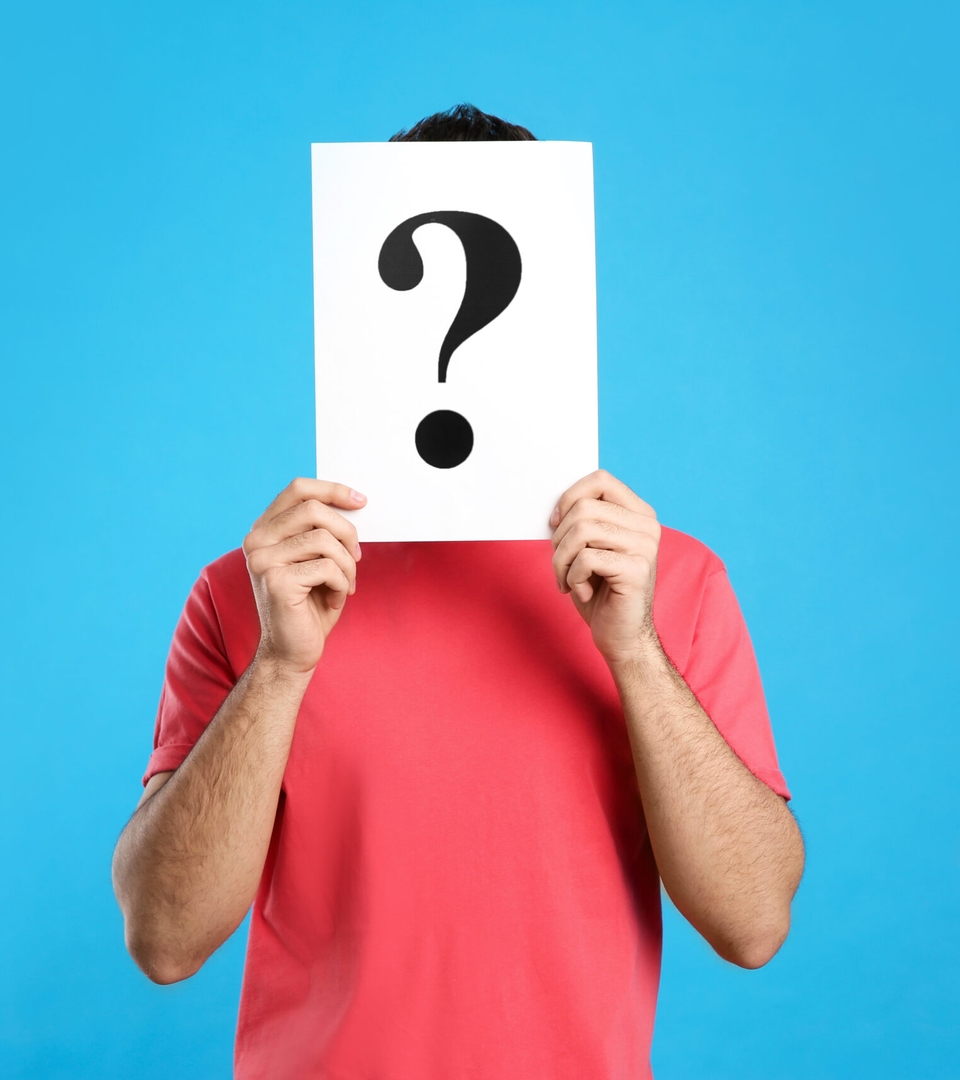 Young man with question mark sign on light blue background